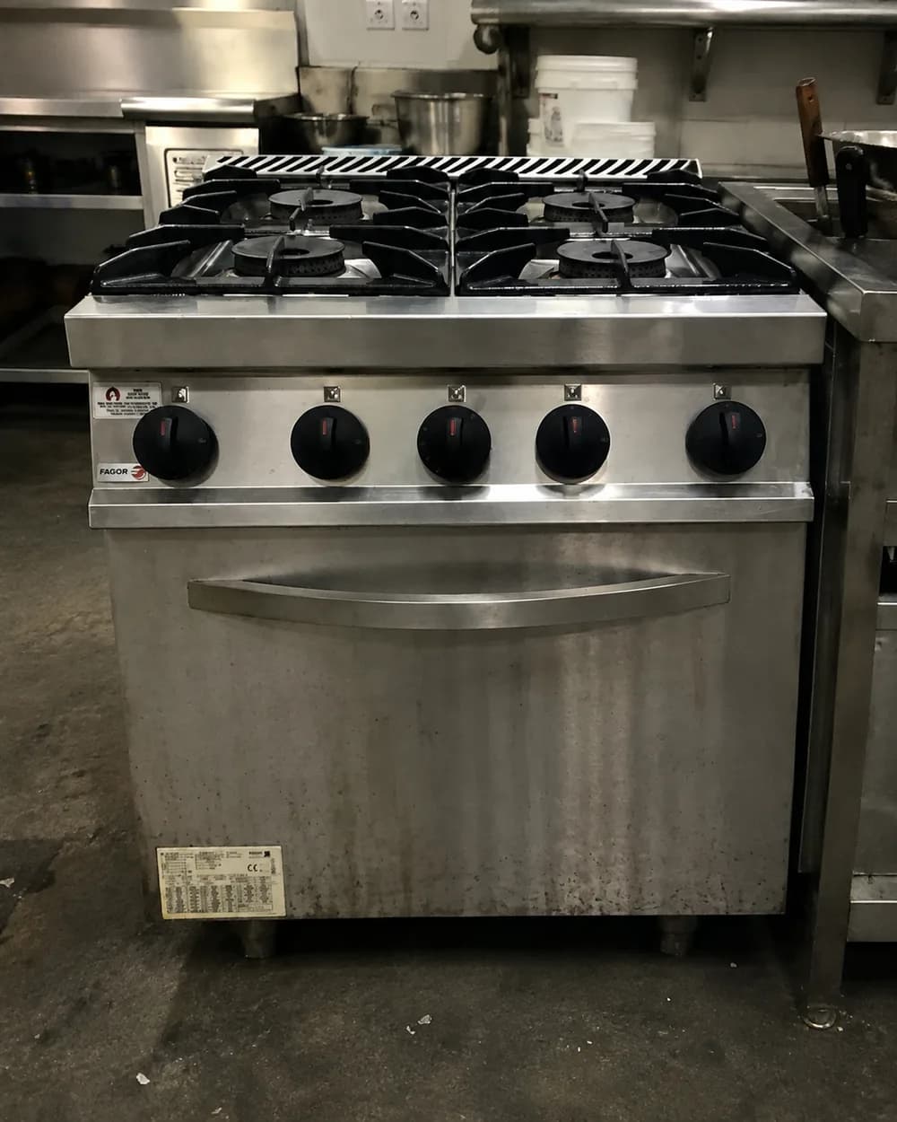 Commercial gas range with four burners and an oven in a commercial kitchen