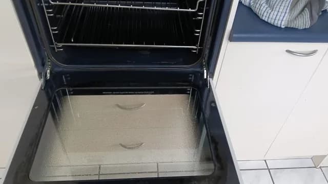 Clean oven door glass reflecting the kitchen cabinetry